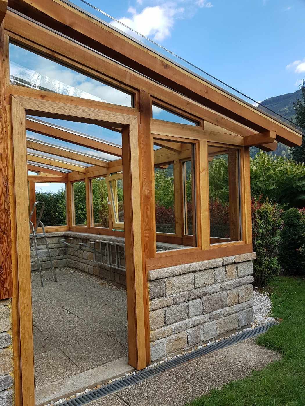 Eine Holzkonstruktion mit Glasdach und vielen Fenstern.