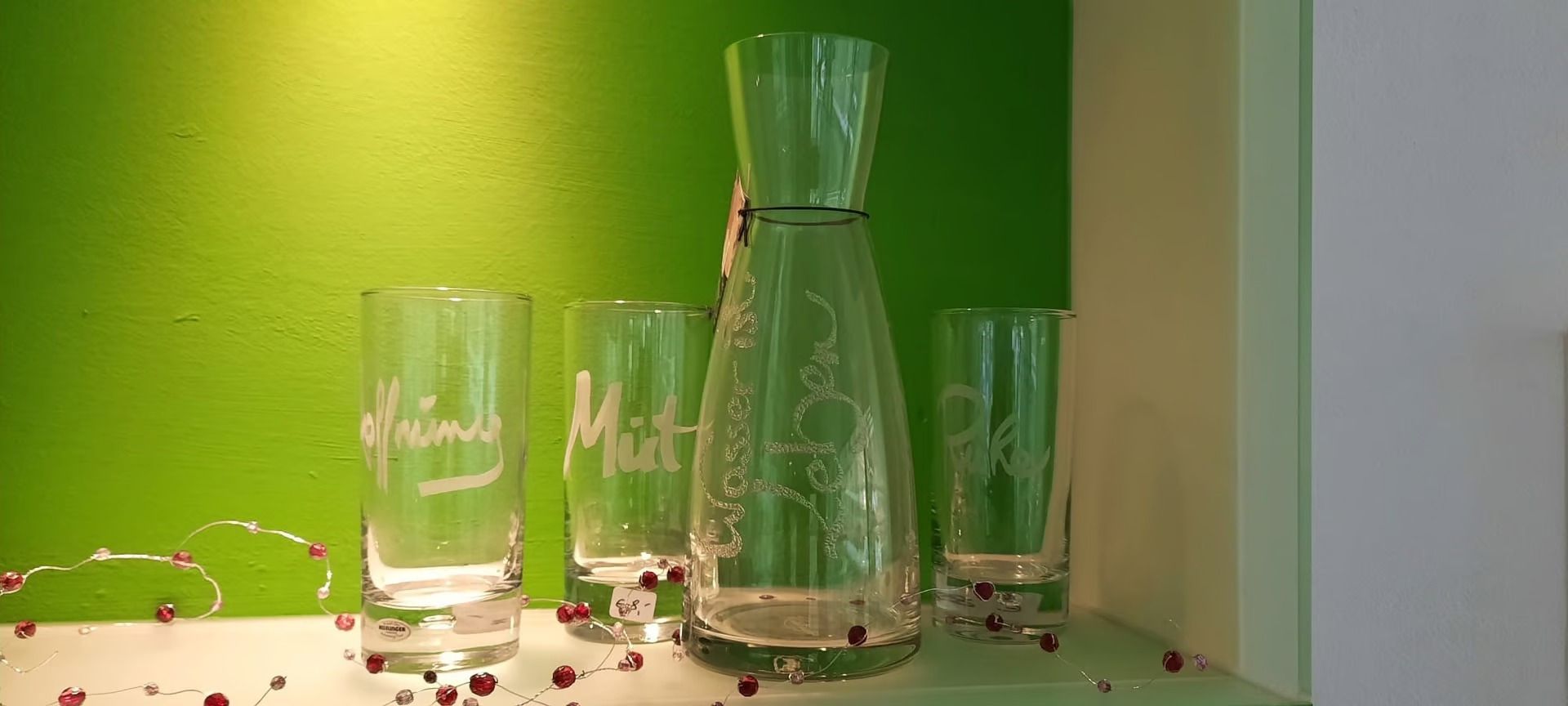 Auf einem Tisch stehen ein Krug und drei Gläser.