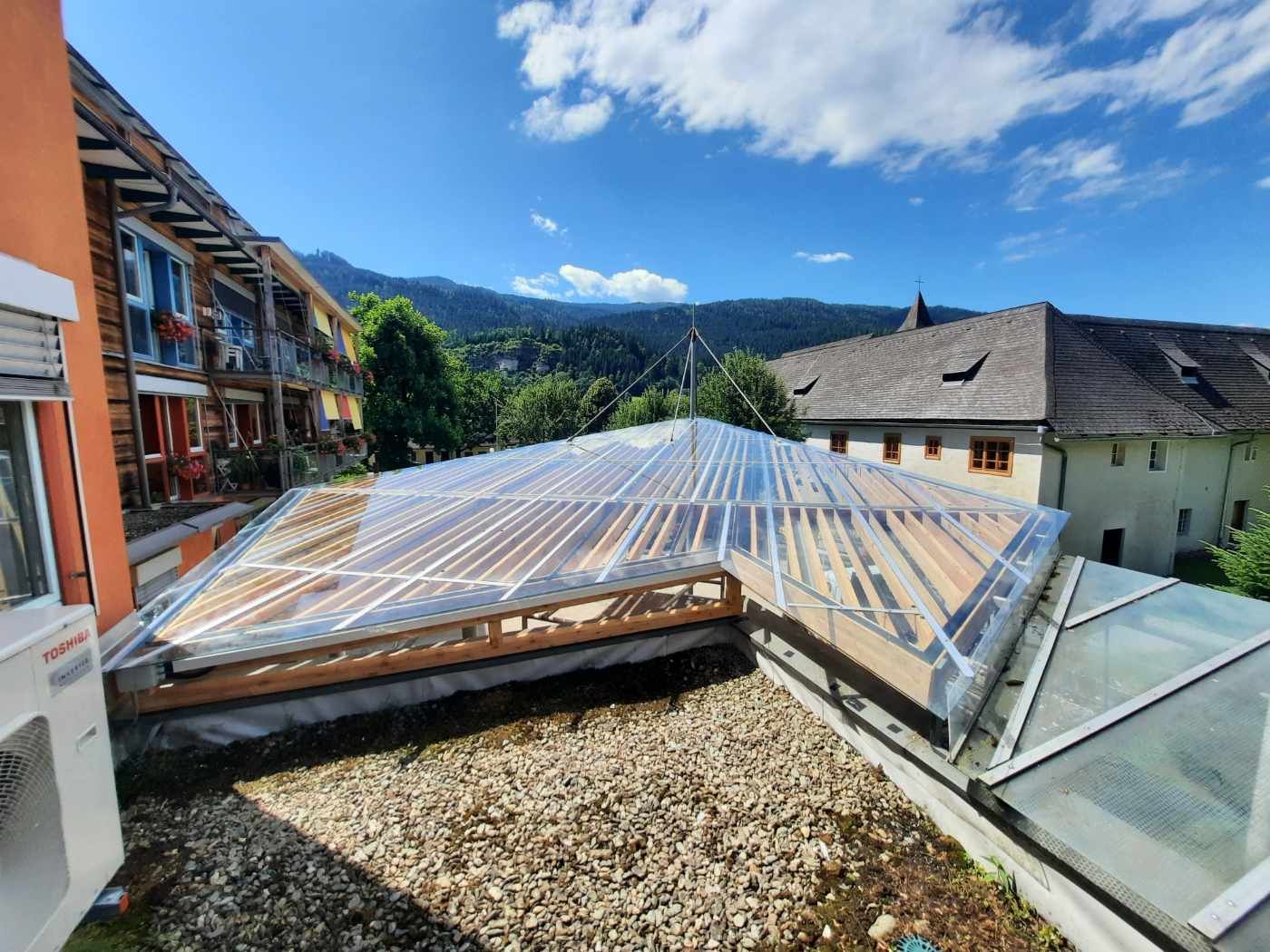 Ein Gebäude mit klarem Dach und Blick auf die Berge.