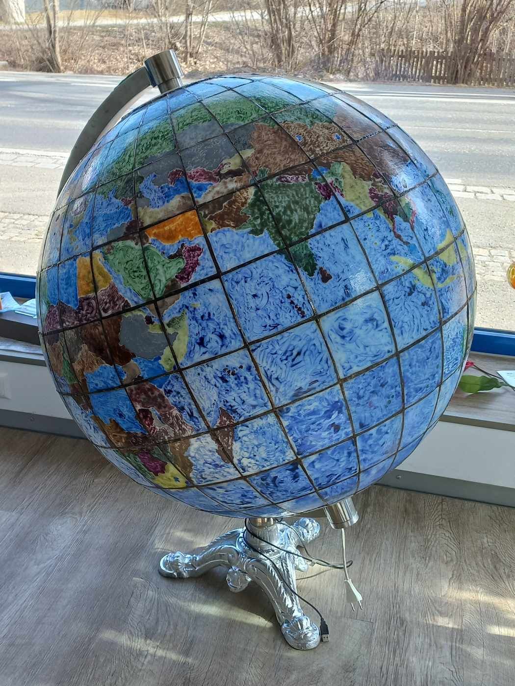 Auf einem Tisch vor einem Fenster steht ein Globus.