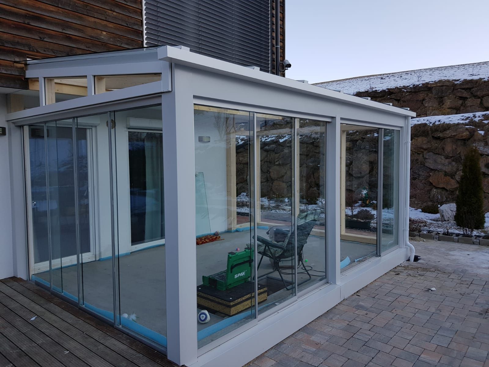 Ein weißer Wintergarten mit Glasschiebetüren und einem Tisch und Stühlen.