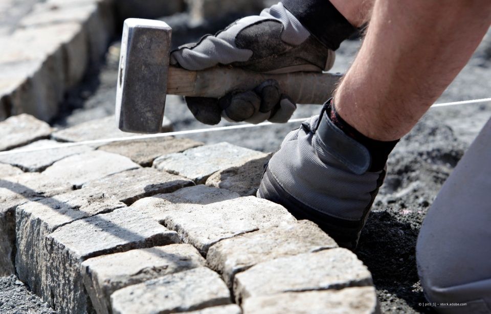 Ein Bauarbeiter benutzt einen Hammer, um Beton zu zerschlagen. Sattler Bau- und Handels GmbH