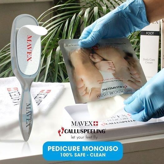 Una persona che indossa guanti blu tiene in mano una confezione di monouso per pedicure