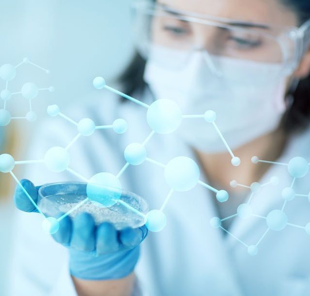 Un científico que lleva una máscara y gafas protectoras sostiene una placa de Petri.