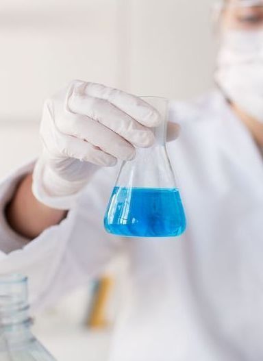 Un científico sostiene un vaso de precipitados con líquido azul dentro.