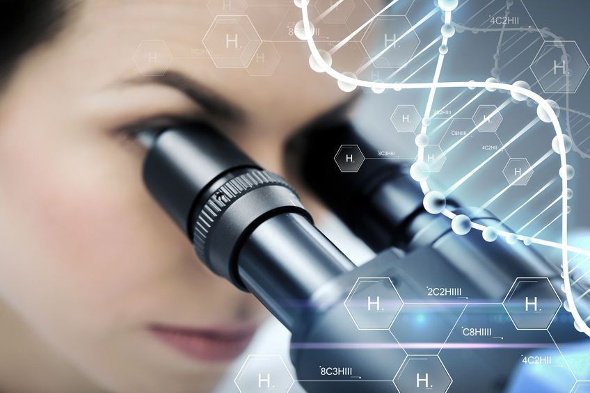 Una mujer está mirando a través de un microscopio con un diagrama de ADN en el fondo.