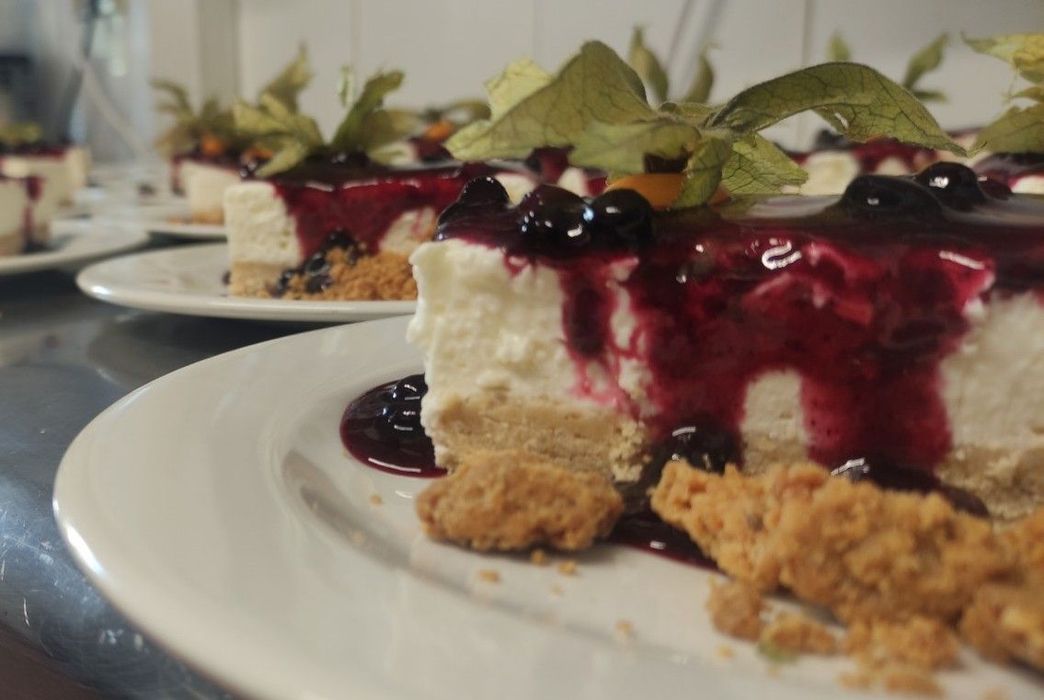 Rebanadas de tarta de queso en platos, cubiertas con salsa de arándanos y grosellas.