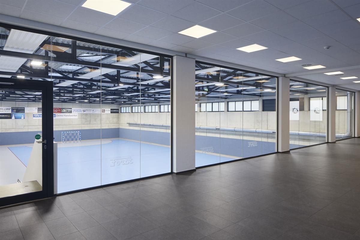 Ein großer Raum mit blauem Boden und vielen Fenstern