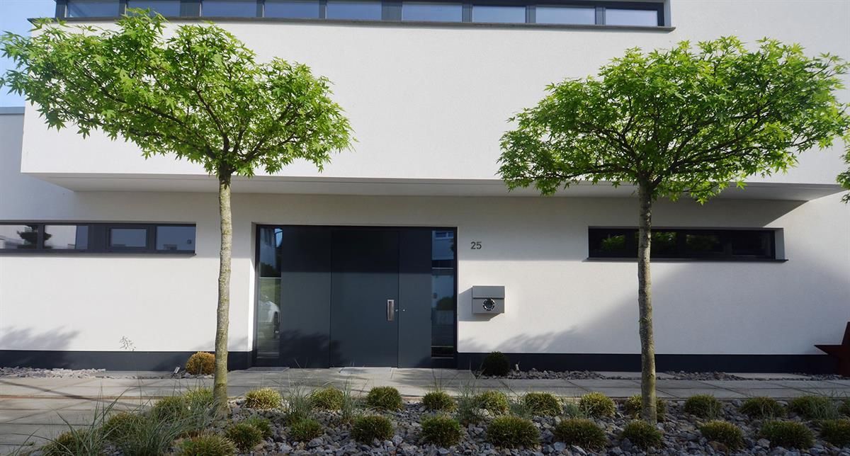 Ein weißes Haus mit Bäumen davor