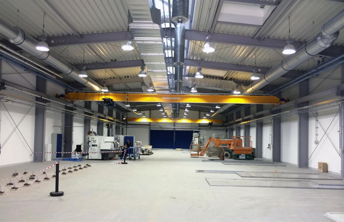 Eine große leere Lagerhalle mit einem gelben Kran in der Mitte