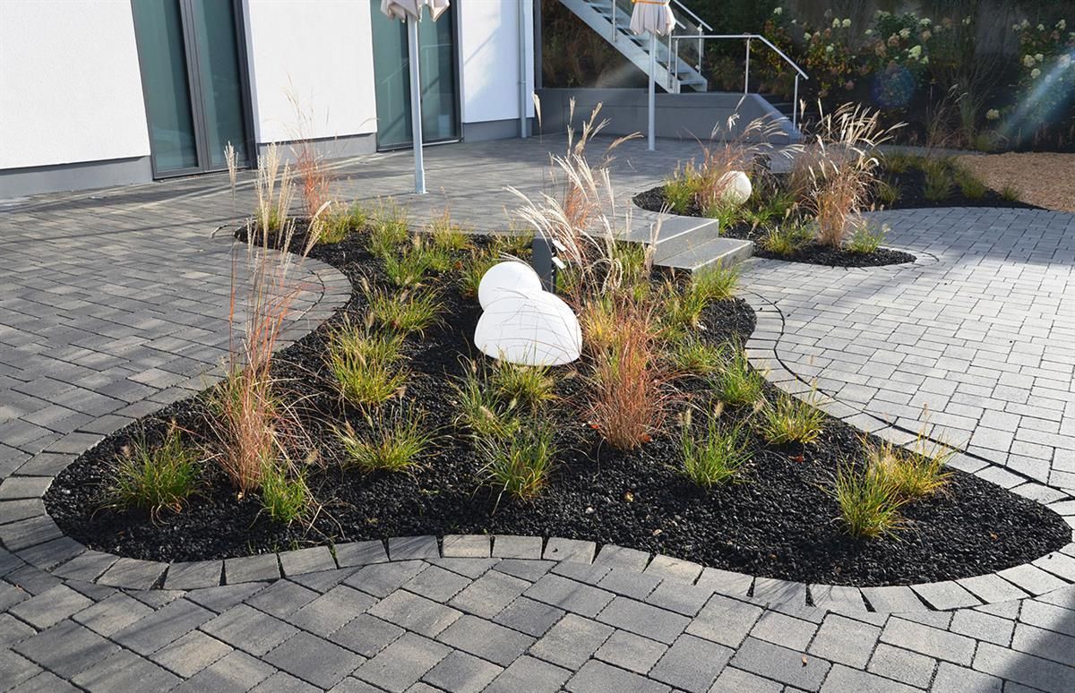 Eine gepflasterte Auffahrt mit Pflanzen und Steinen darin