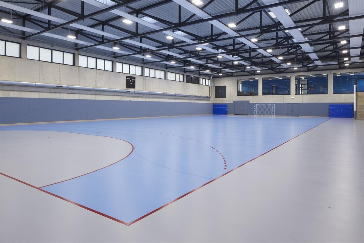 Eine leere Turnhalle mit blauem Boden und roten Linien