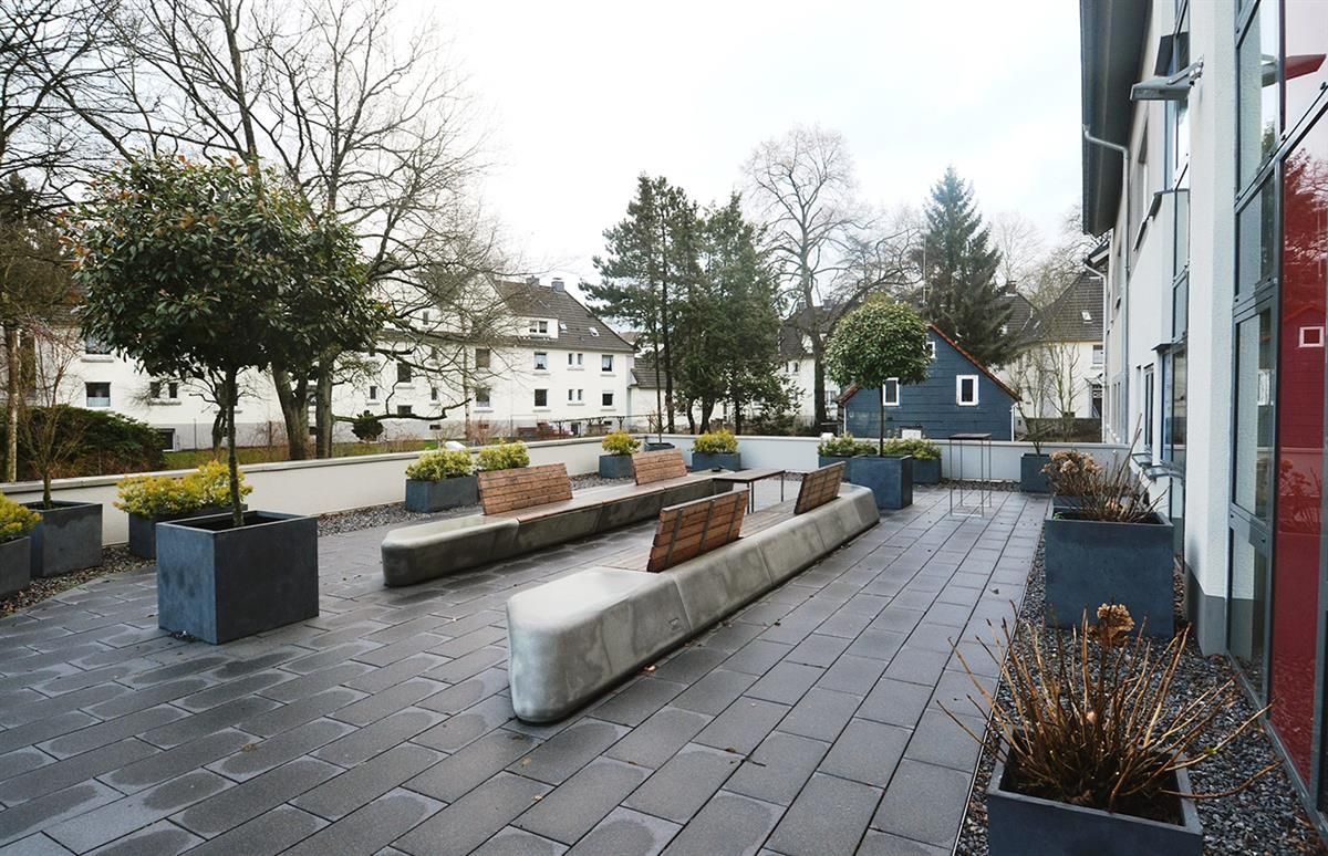 Eine Terrasse mit Pflanzkübeln und Bänken vor einem Gebäude