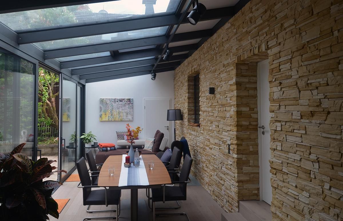 Ein Esszimmer mit Tisch und Stühlen unter einem Glasdach