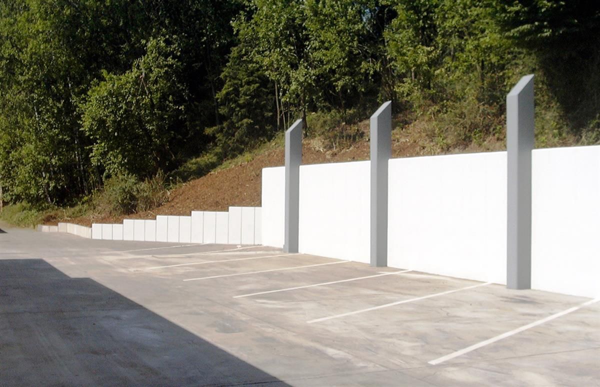 Ein Parkplatz mit einer weißen Wand und Bäumen im Hintergrund