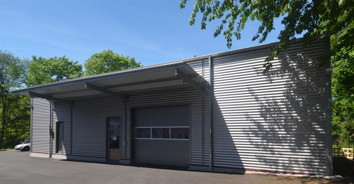 Ein weißes Gebäude mit einem Garagentor ist von Bäumen umgeben