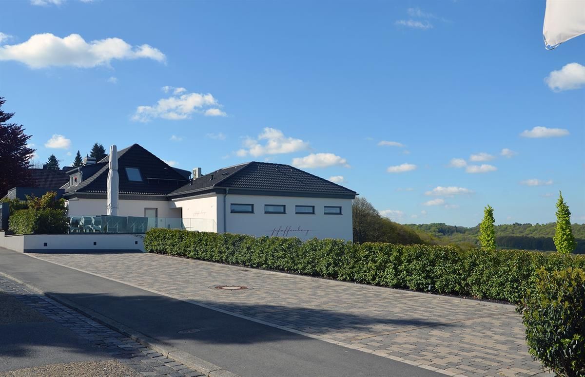 Ein weißes Haus mit schwarzem Dach steht am Straßenrand