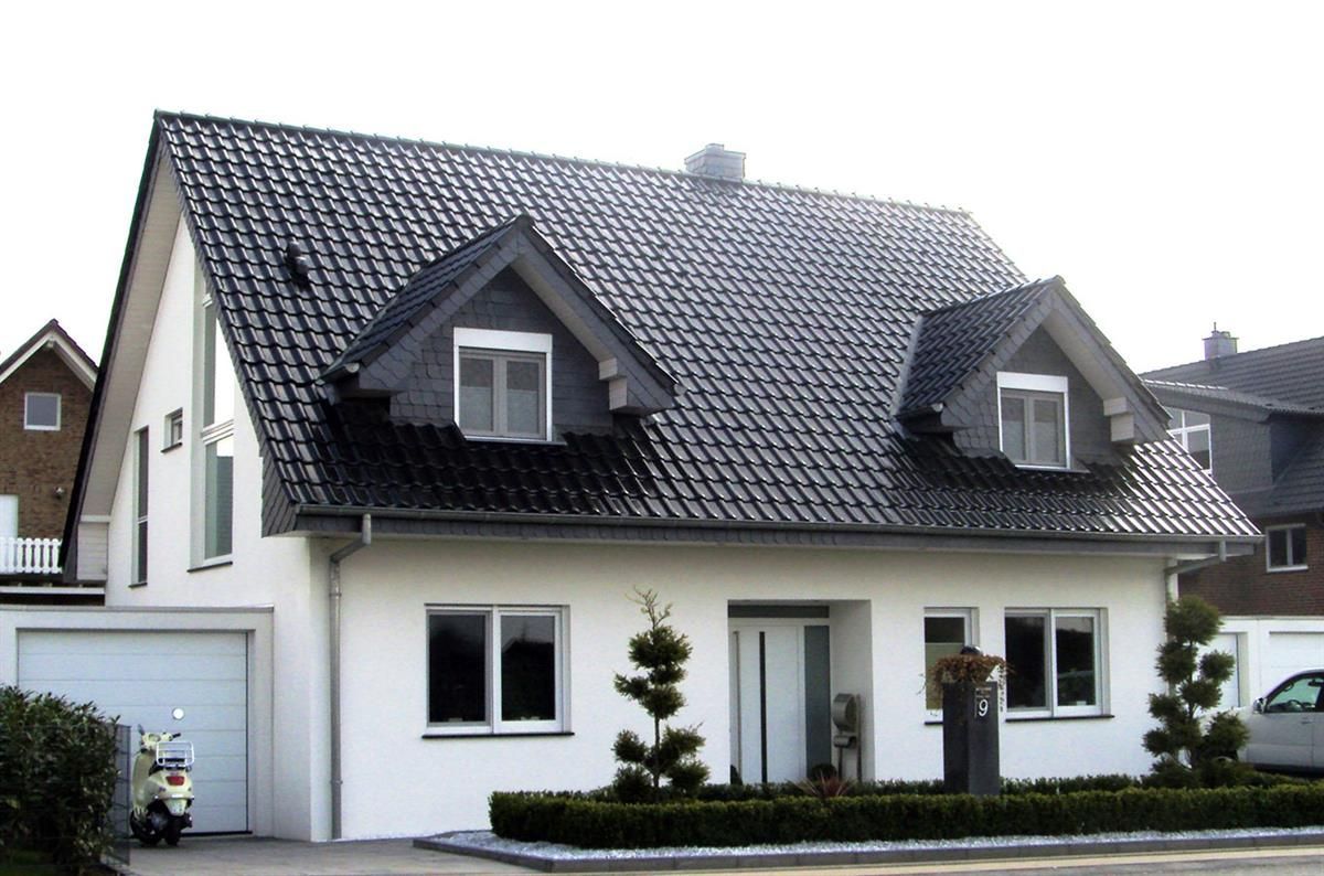 Ein weißes Haus mit schwarzem Dach und einer Garage