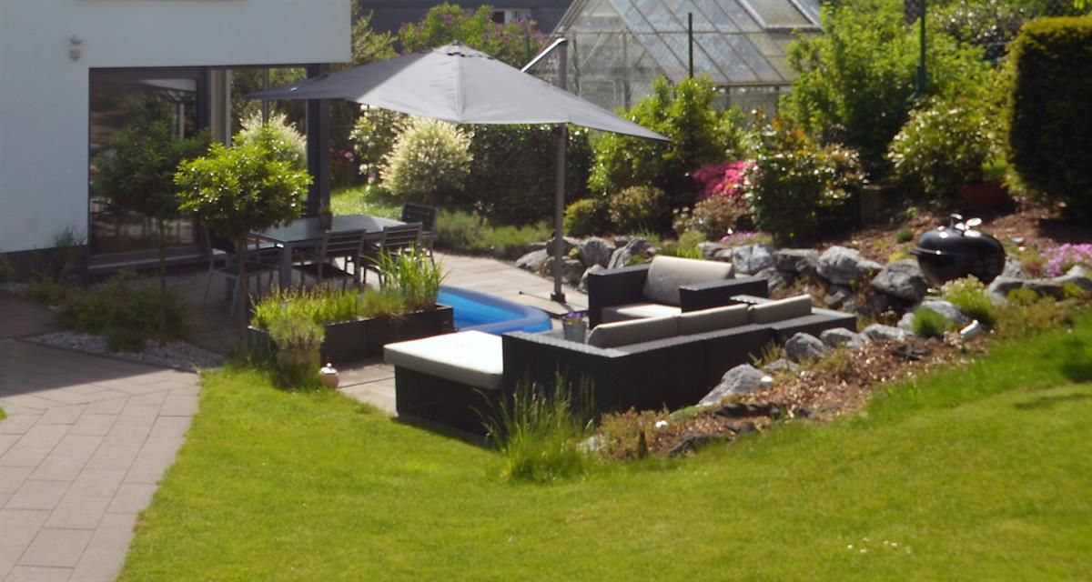 Eine Terrasse mit großem Sonnenschirm und Swimmingpool