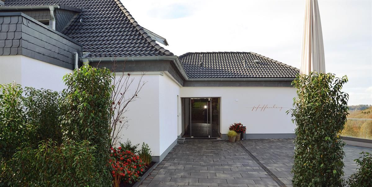 Ein weißes Haus mit schwarzem Dach und einer Auffahrt, die dorthin führt