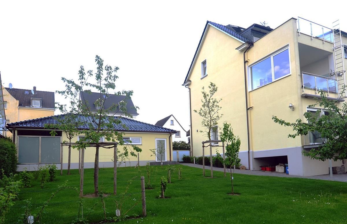 Ein gelbes Haus mit blauem Dach ist von Bäumen umgeben