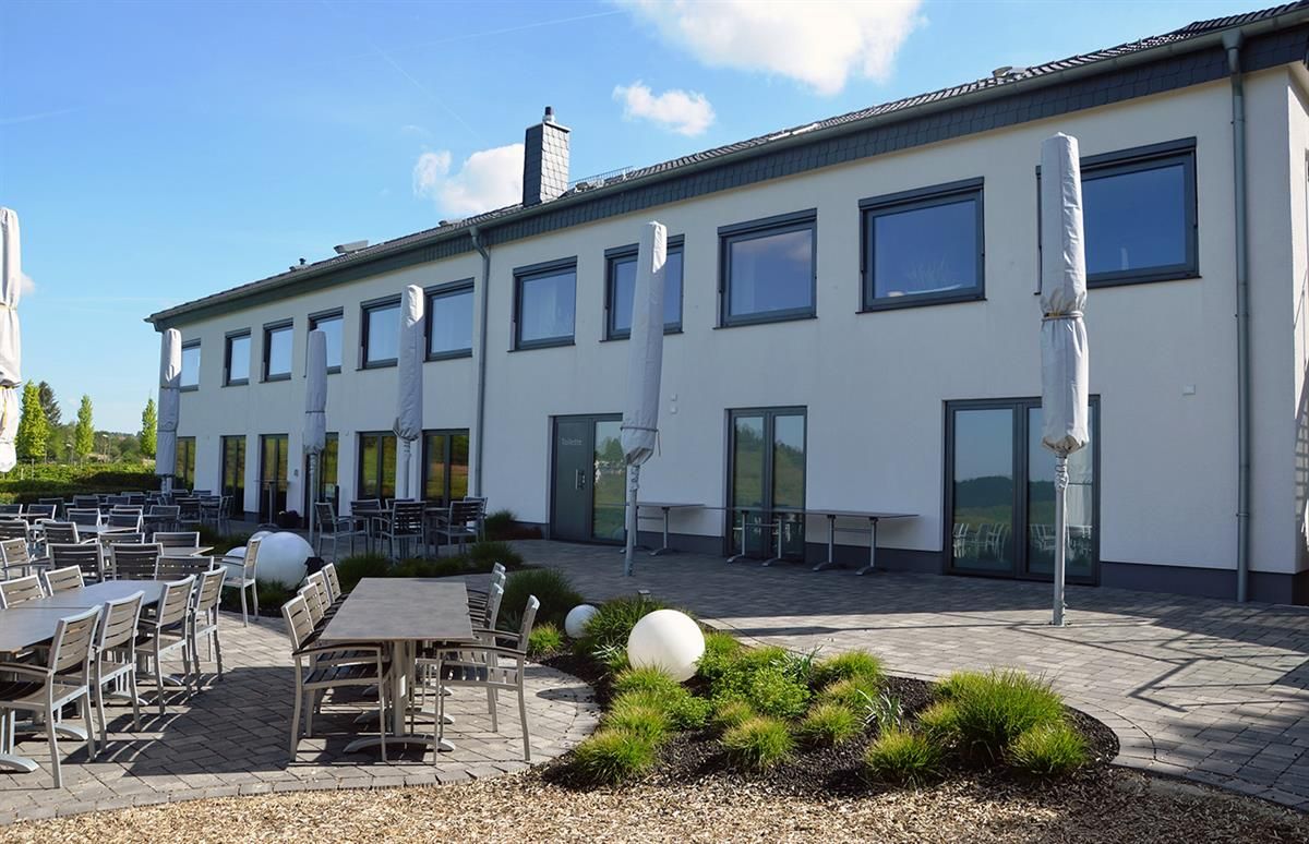 Ein großes weißes Gebäude mit Tischen und Stühlen davor