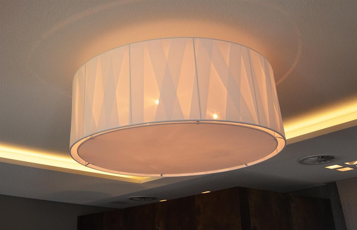 Eine Deckenleuchte mit weißem Schirm leuchtet