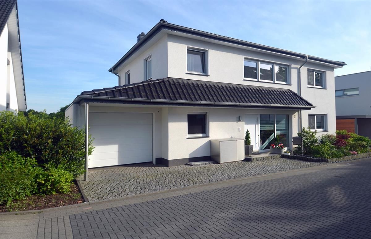 Ein weißes Haus mit schwarzem Dach steht auf einer Kopfsteinpflasterstraße