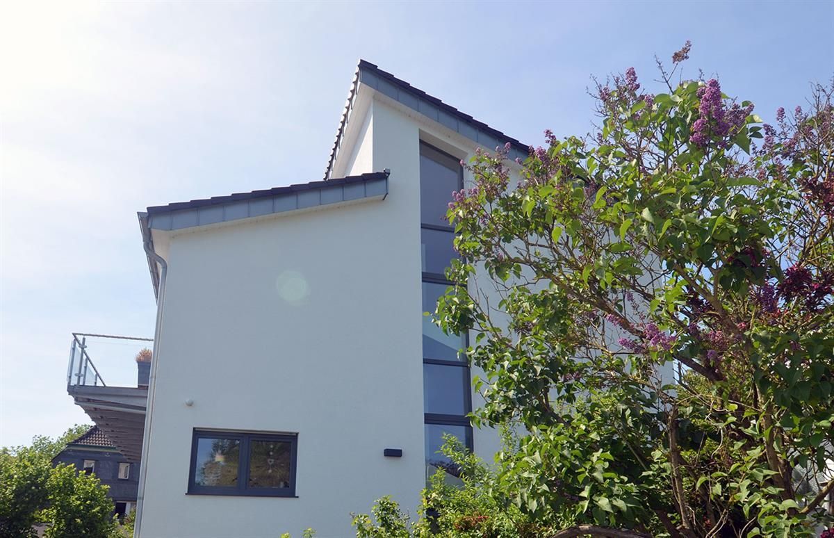 Ein weißes Haus mit einem Balkon und einem Baum davor