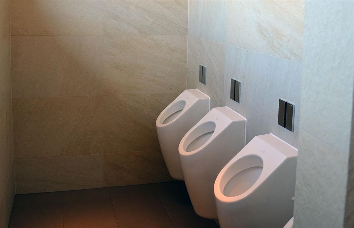 Drei Urinale sind an einer Wand in einem Badezimmer aufgereiht