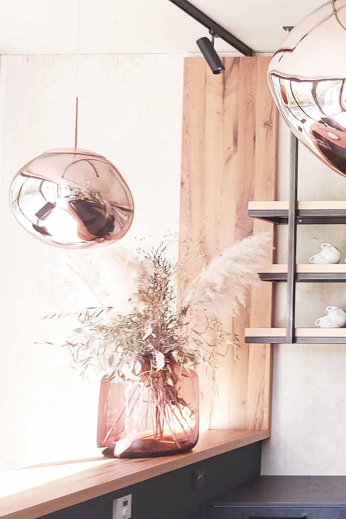 Eine Vase mit Blumen steht auf einer Theke neben einem Fenster