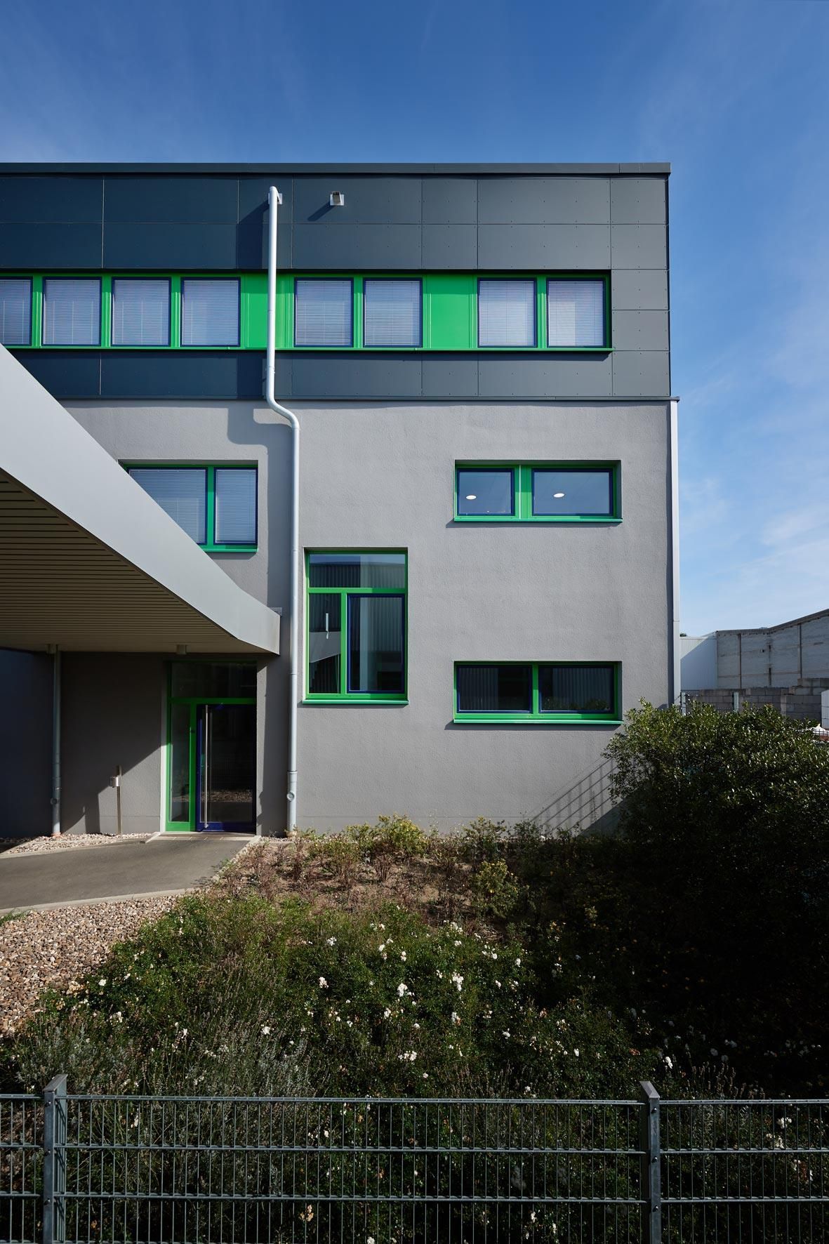 Ein Gebäude mit grünen Fenstern und einem Zaun davor