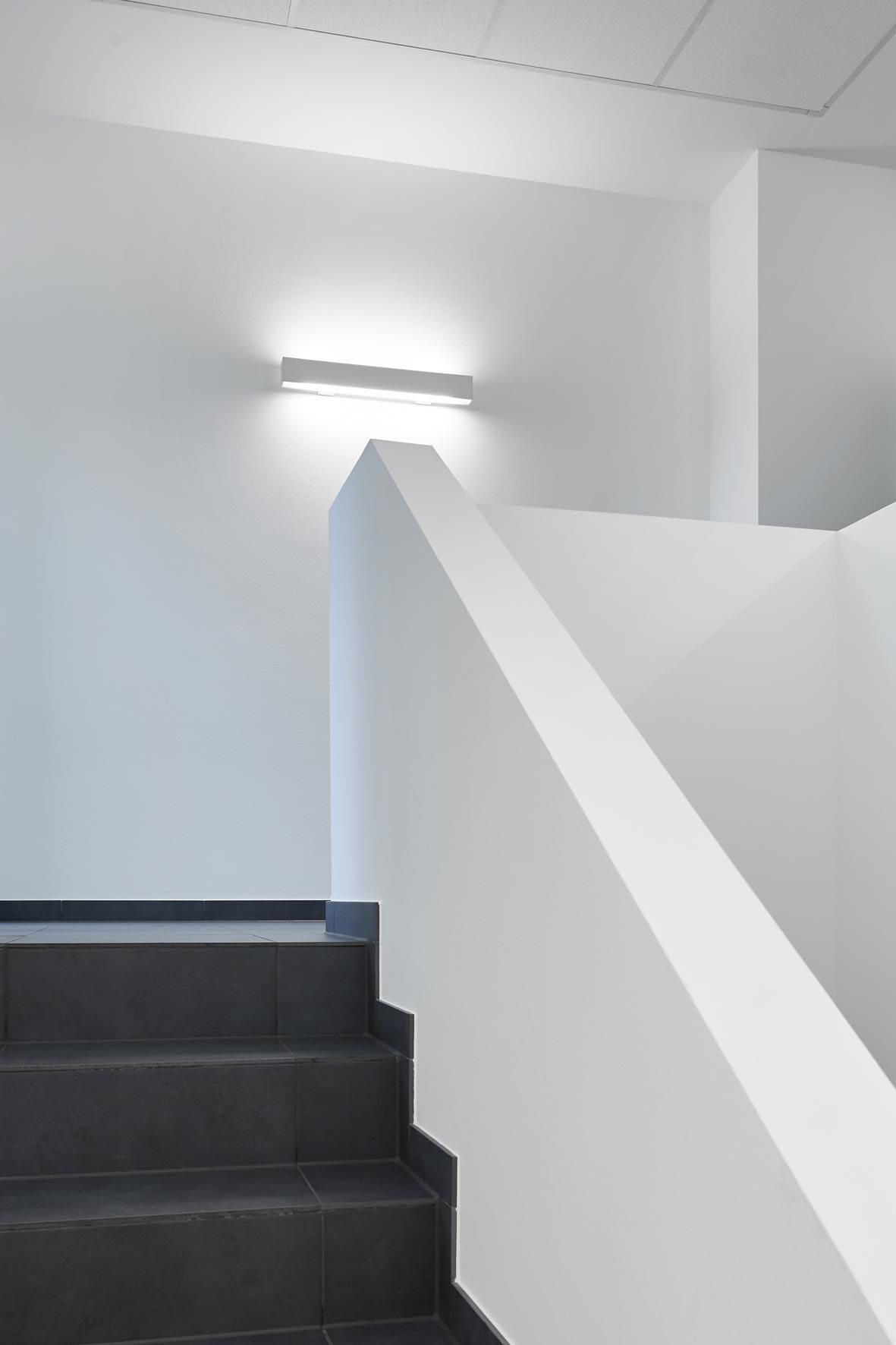 Eine Treppe mit einem weißen Geländer und einem Licht an der Wand