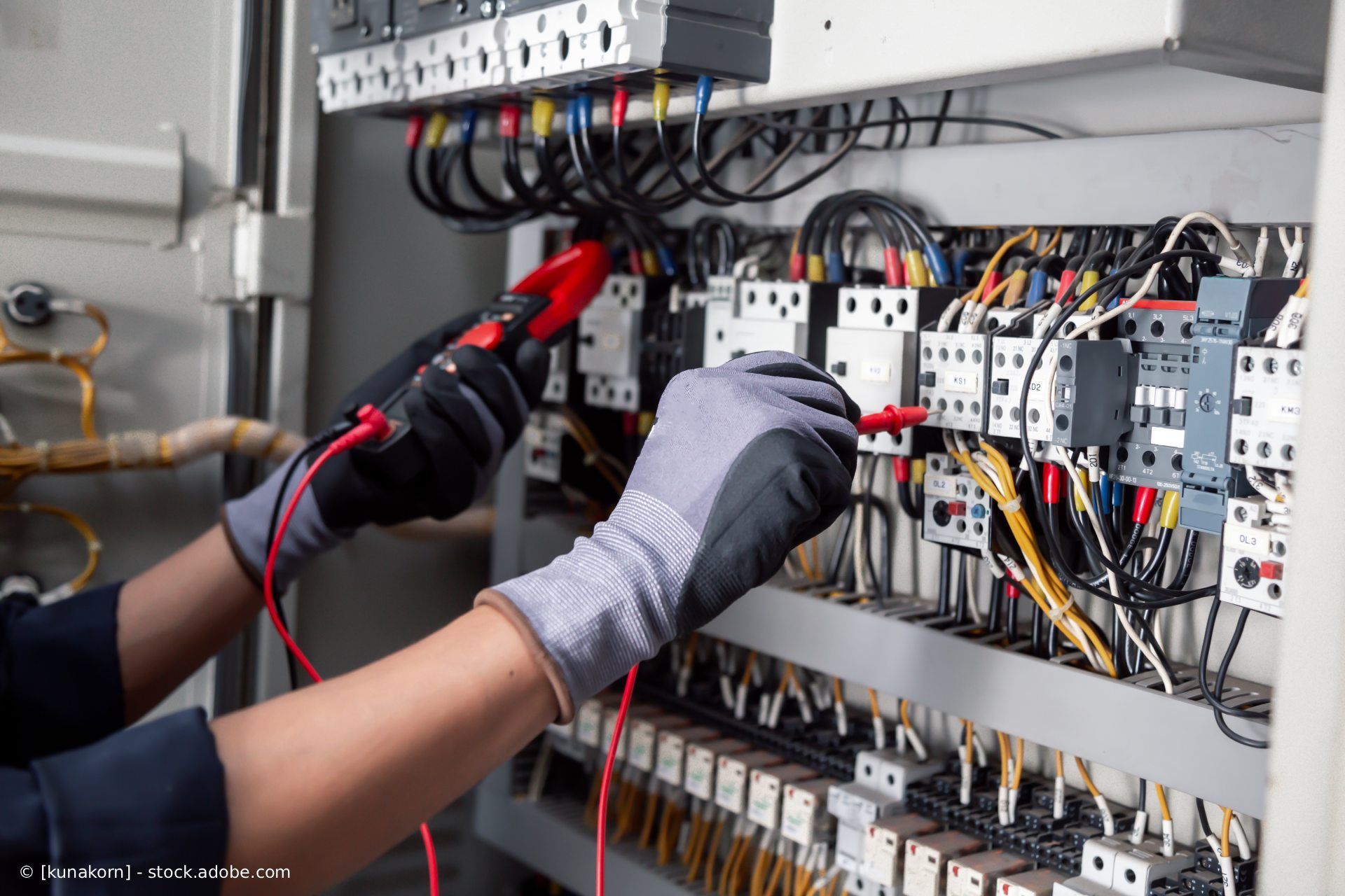 Innenansicht einer Baustelle mit einer Holzrahmenwand, an deren Seite ein Bündel weißer elektrischer Drähte hängt.