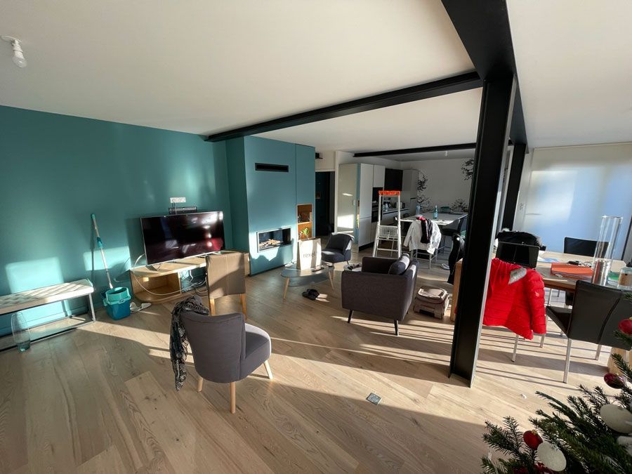 Pièce principale d'une maison avec des piliers noirs et des fauteuils