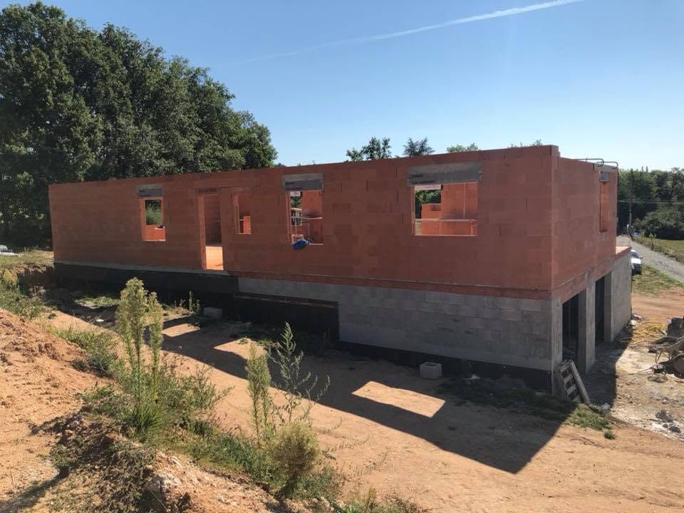 Maison en briques partiellement construite sur des fondations en béton surélevées, en zone rurale