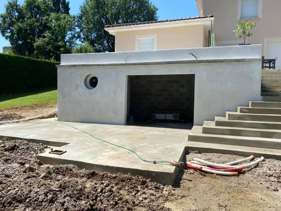 Extérieur de maison moderne avec ouverture de garage, allée en béton et marches donnant sur une cour en terre.