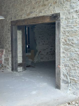 Porte en pierre donnant sur une pièce sombre et inachevée aux murs bruts et au sol en béton