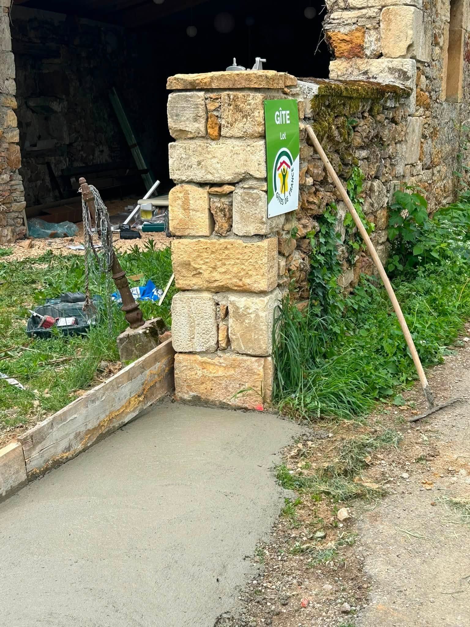 Pilier de pierre à côté de l'entrée d'une maison avec un panneau vert.