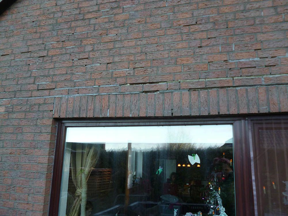 Ein Backsteingebäude mit einem großen Fenster und einem Weihnachtsbaum im Fenster.