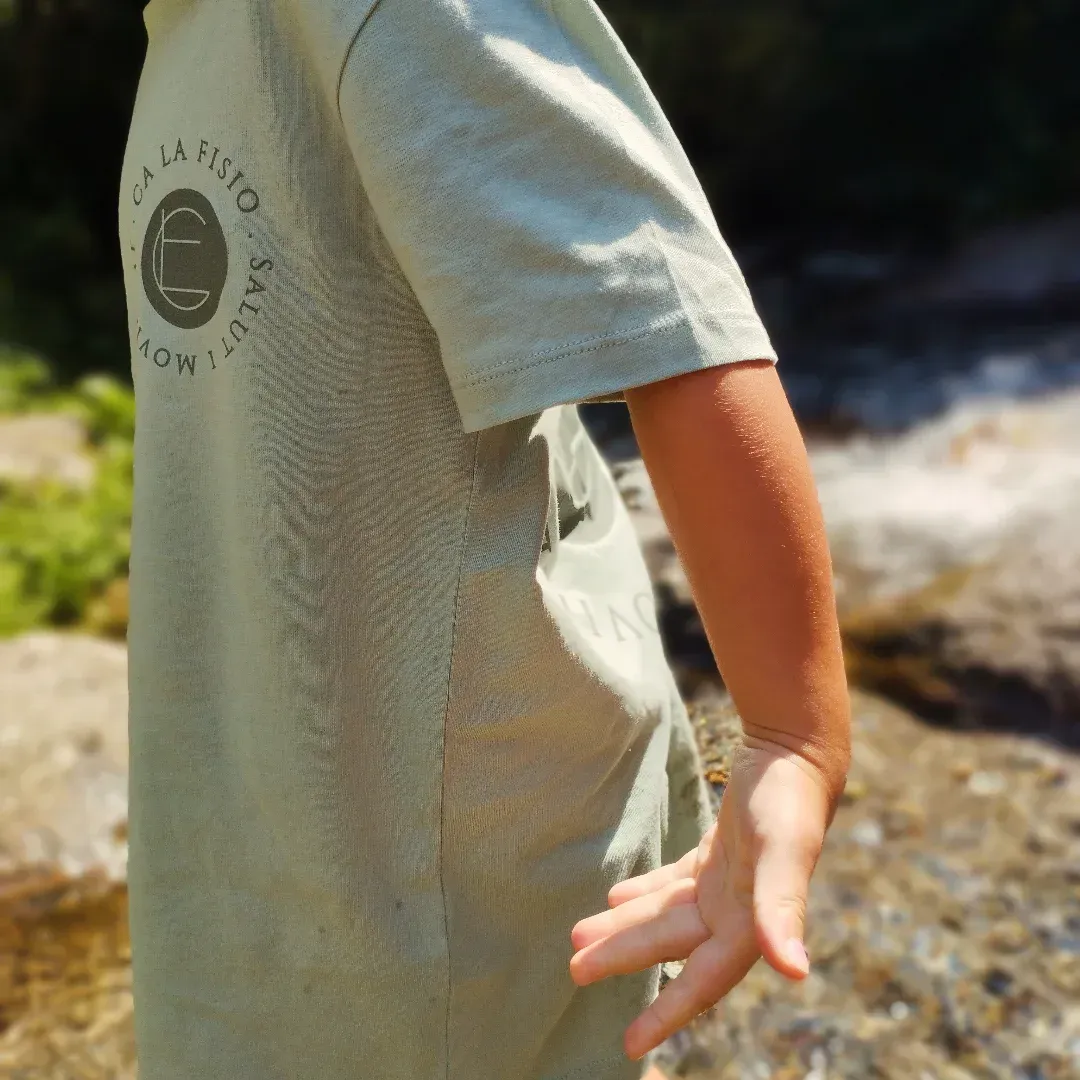Primer plano de una persona con una camiseta verde salvia con un logotipo circular