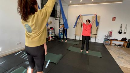 Una persona vestida con ropa deportiva negra realiza una postura de yoga en forma de V