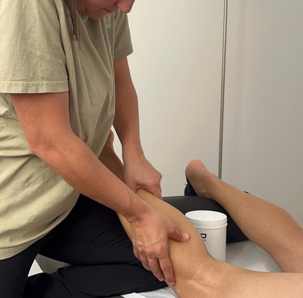 Una persona recibe un masaje en la pantorrilla por parte de un terapeuta, quien presiona firmemente el músculo con las manos.
