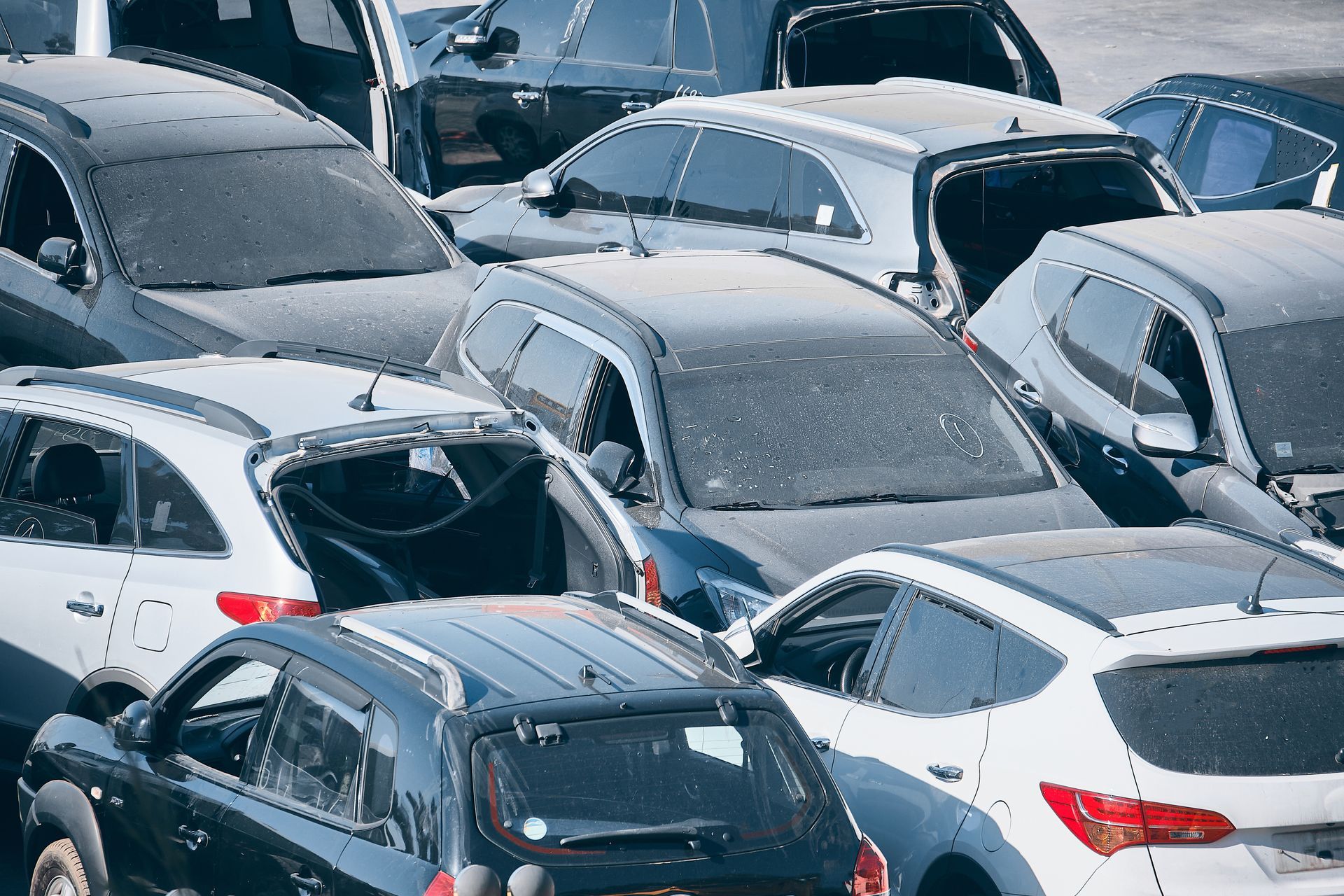 Un ensemble de voitures diverses, entassées les unes contre les autres sur un terrain vague poussiéreux.