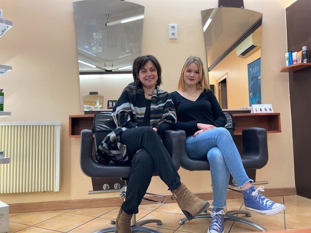 Deux coiffeuses du salon assises sur des fauteuils jambes croisées