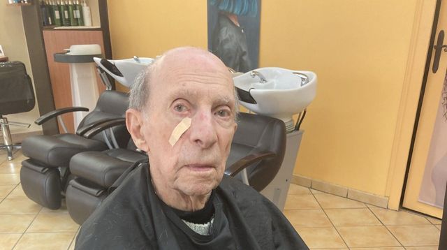 Monsieur âgé avec une blouse de protection et devant un bac à shampoing