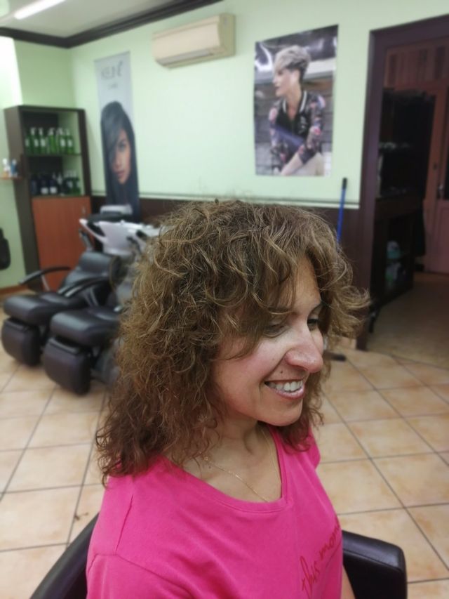 Femme souriante avec cheveux bouclés châtains après une permanente