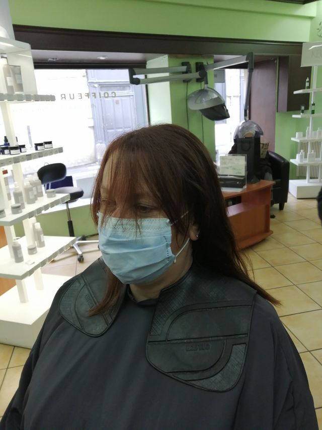 Femme aux cheveux châtains mi-longs portant masque et blouse