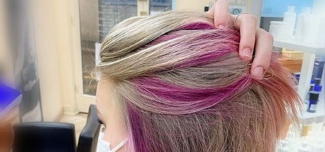 Femme qui se passe les doigts dans ses cheveux avec mèches roses