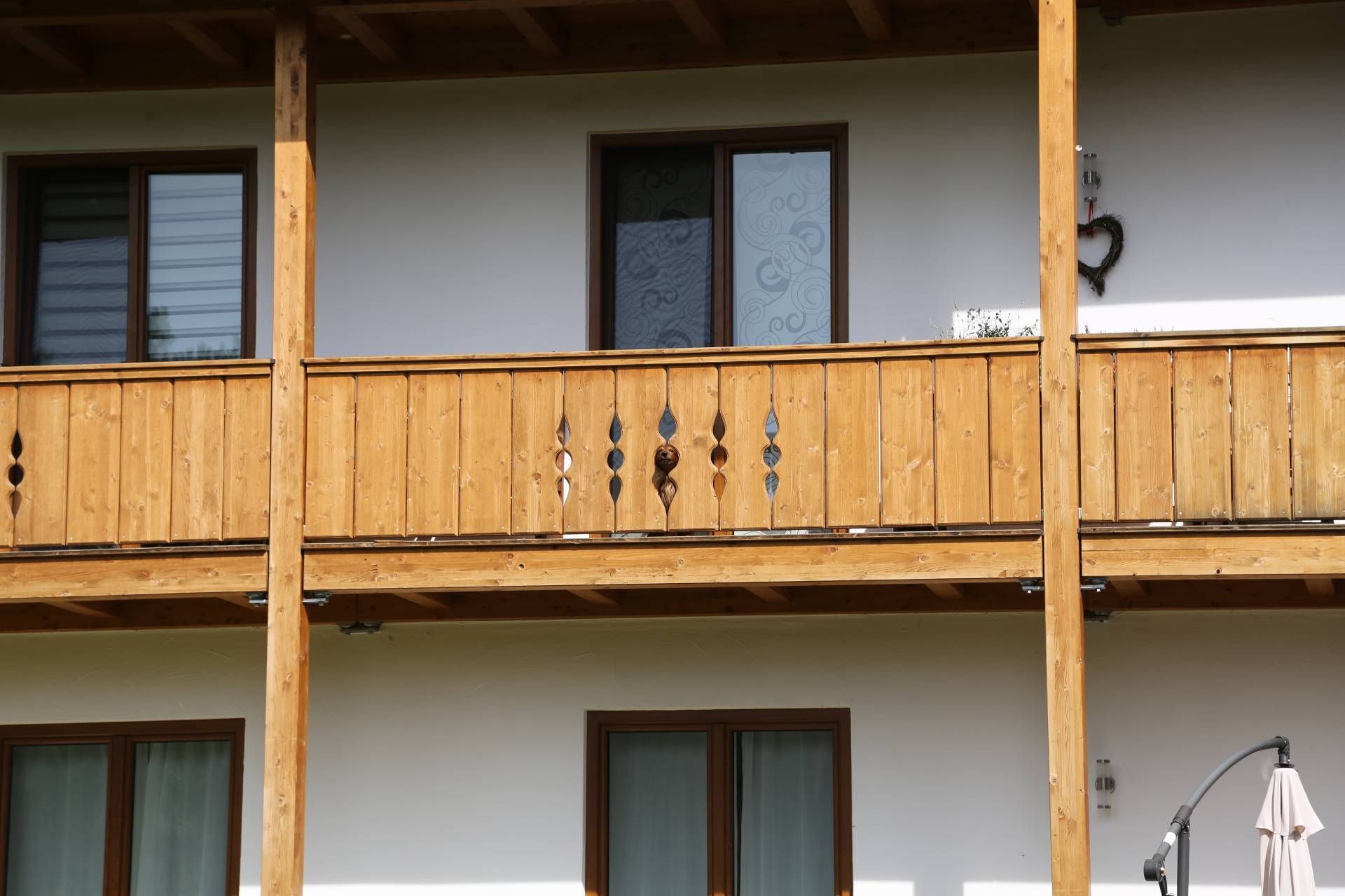 ein weißes Haus mit einem Holzbalkon und vielen Fenstern